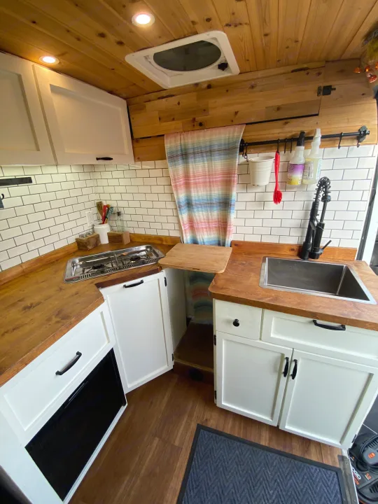 Cozy van kitchen/galley for your next RV rental adventure. Features wood accents, subway tile, stove, sink, and cabinets.. Other Other 2015