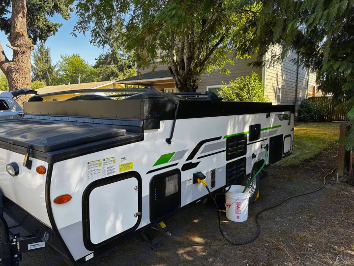This A-frame RV rental is set up with power and water connections outdoors, perfect for a cozy getaway.. Forest River A122S 2021