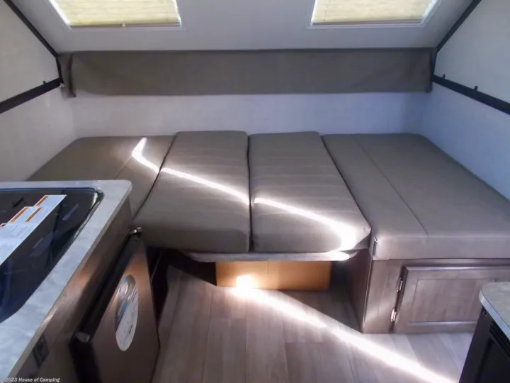 This RV rental interior features a versatile bed/seating area made of modular cushions, a compact kitchenette, and bright skylights.. Forest River A122S 2021