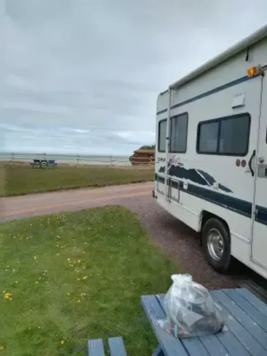 Enjoy your RV rental by the scenic coast! This motorhome is parked at a beachside campsite with a picnic table and ocean view.. Chevrolet Other 1996