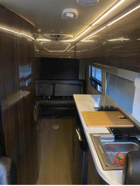 Modern RV rental interior: galley kitchen, comfortable rear lounge/bed, wood floors, and bright overhead LED lighting.. Winnebago Era 2017