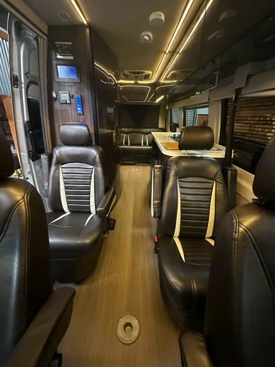 Step into comfort! This spacious luxury RV rental interior features captain's chairs, a kitchenette, and rear lounge.. Winnebago Era 2017