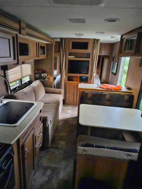 Step inside this Apex RV rental: a cozy living space with kitchen, dining booth, and sofa. Perfect for travel!. Coachmen Apex 50th Anniversary 2015