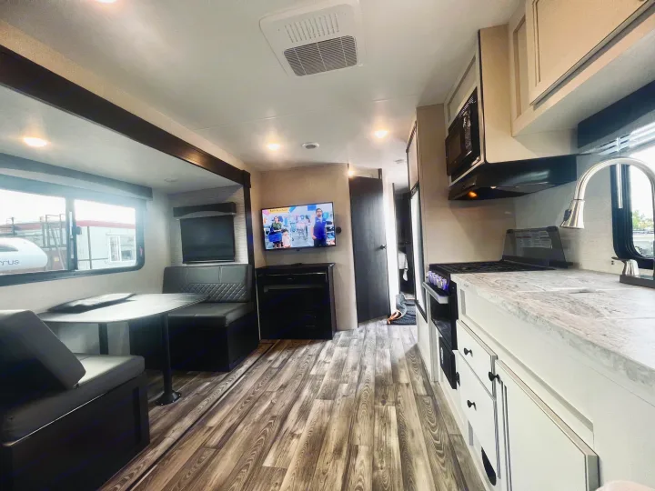 Experience comfort in this RV rental! Features a modern kitchen, dinette, living space with TV, and stylish wood floors.. Highland Ridge RV Range Lite 2022