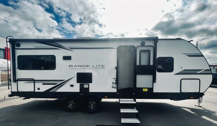 White Range Lite travel trailer with an open door and steps, ready for your next RV rental adventure.. Highland Ridge RV Range Lite 2022