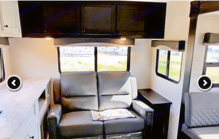 RV rental interior shows a cozy living area with a black leather sofa, windows, and overhead cabinets.. Highland Ridge RV Range Lite 2022