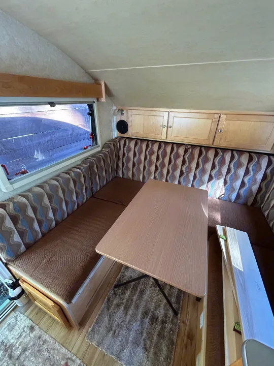Spacious RV rental dinette with comfortable U-shaped seating, central table, and overhead storage.. T@B Q Floorplan Maxx Package 2016