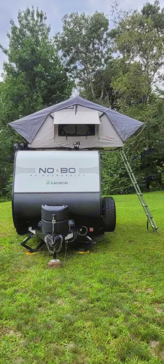 RV rental: Compact travel trailer with a pop-up rooftop tent & ladder, ready for your outdoor adventure on green grass.. Forest River NoBo 10.6 2022