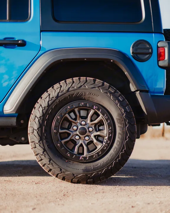 Side view of a blue Jeep Wrangler, highlighting its rugged BFGoodrich off-road tire and wheel. Great for any adventure or rv rental trip.. Jeep Wrangler 2022
