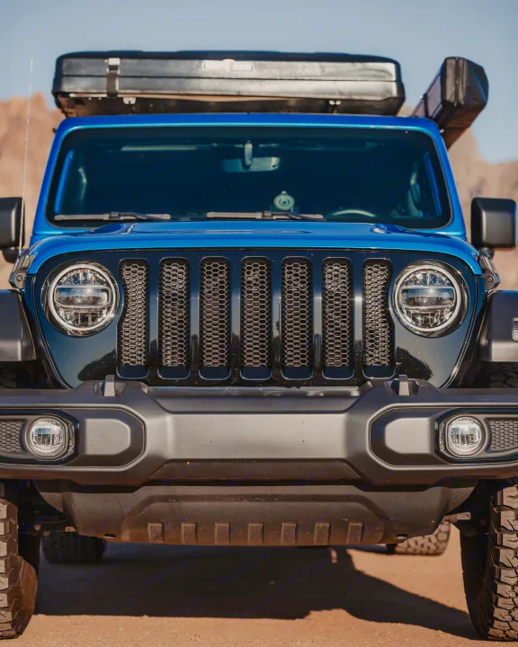 Close-up frontal view of a blue Jeep Wrangler with a rooftop tent, ideal for your next RV rental adventure.. Jeep Wrangler 2022