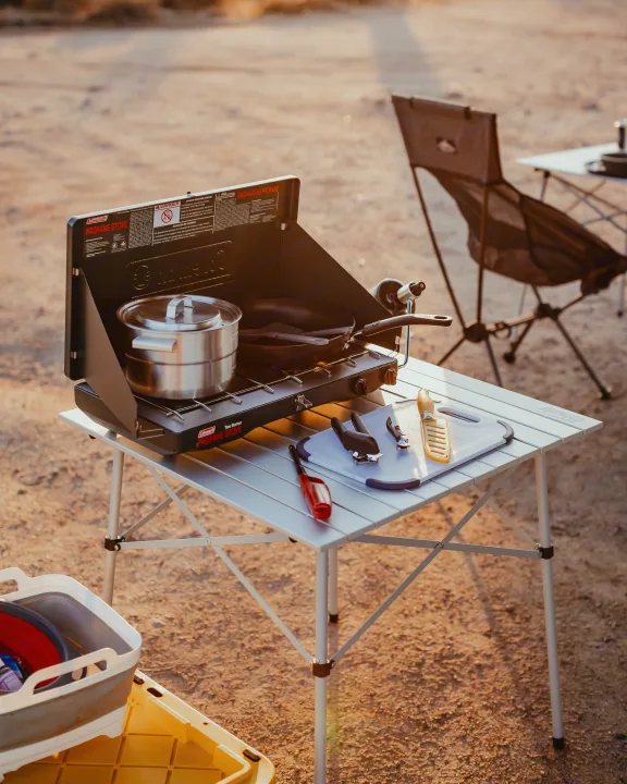 Outdoor cooking during an RV rental trip, featuring a Coleman propane stove and portable camp kitchen setup.. Jeep Wrangler 2022