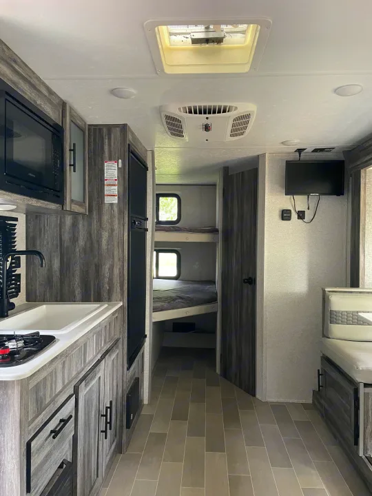 Modern RV rental interior showcasing kitchen, two bunk beds, and a cozy dinette area.. Forest River Salem FSX 2020