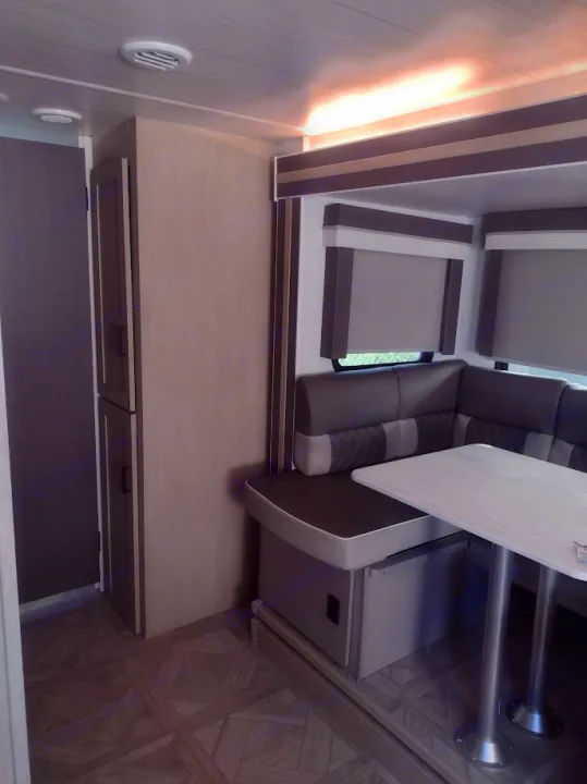 Inside a modern RV rental: an L-shaped dinette with a table, window shades, and storage cabinets, all in neutral tones.. Forest River Salem Cruise Lite 2023