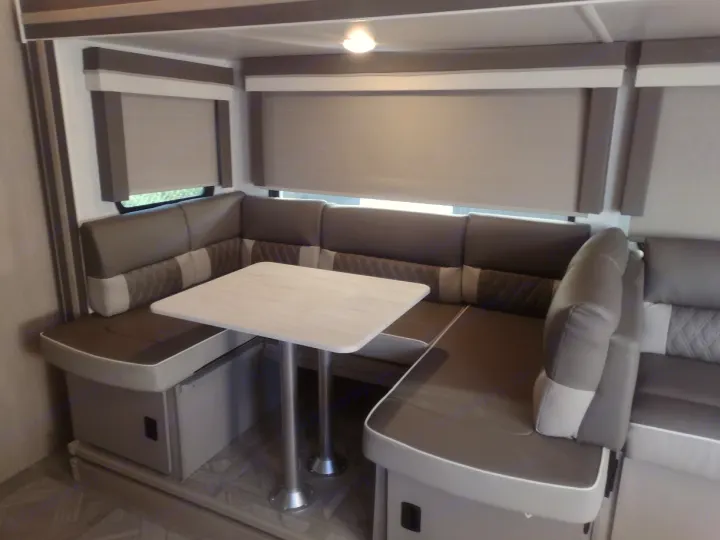 Spacious U-shaped dinette with grey upholstered seating & white table in a modern RV rental interior.. Forest River Salem Cruise Lite 2023