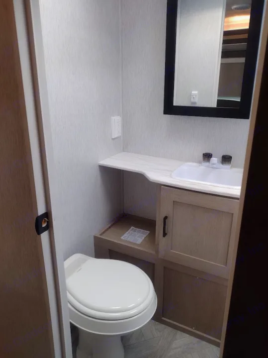 Clean RV rental bathroom featuring a white toilet, sink, mirror, and light wood vanity with storage.. Forest River Salem Cruise Lite 2023