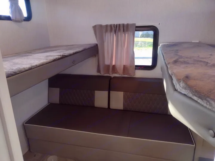RV rental interior: two plush bunk beds flank a comfy dinette sofa with accent cushions, perfect for relaxing or sleeping.. Forest River Salem Cruise Lite 2023