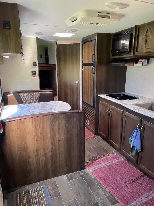 Explore this RV rental's spacious interior: dinette, well-equipped kitchen with stove/microwave, and cozy bunk beds.. Keystone RV Bullet Crossfire 2019