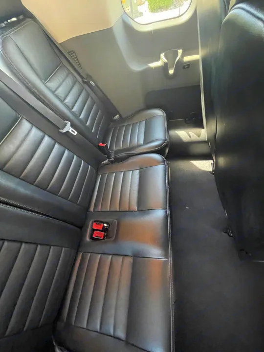 Inside an RV rental: spacious rear black leather seats with seatbelts, ready for travel.. Ford Transit 350 XLT 2020