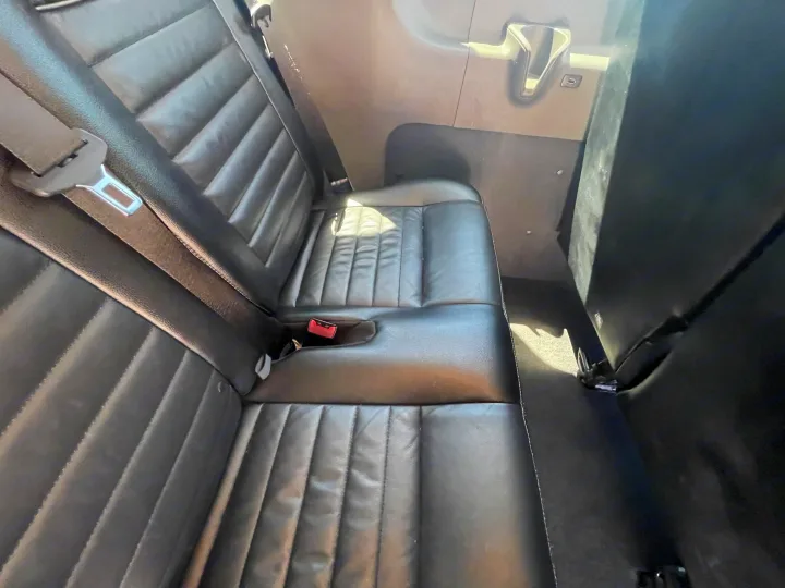 Black leather rear seating with seatbelts and interior paneling, a functional space in this RV rental.. Ford Transit 350 XLT 2020