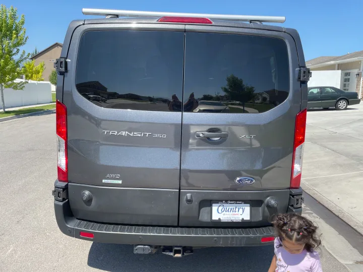 Rear of a gray Ford Transit 350 XLT AWD van, ideal for an **rv rental** conversion, featuring a roof rack and hitch.. Ford Transit 350 XLT 2020