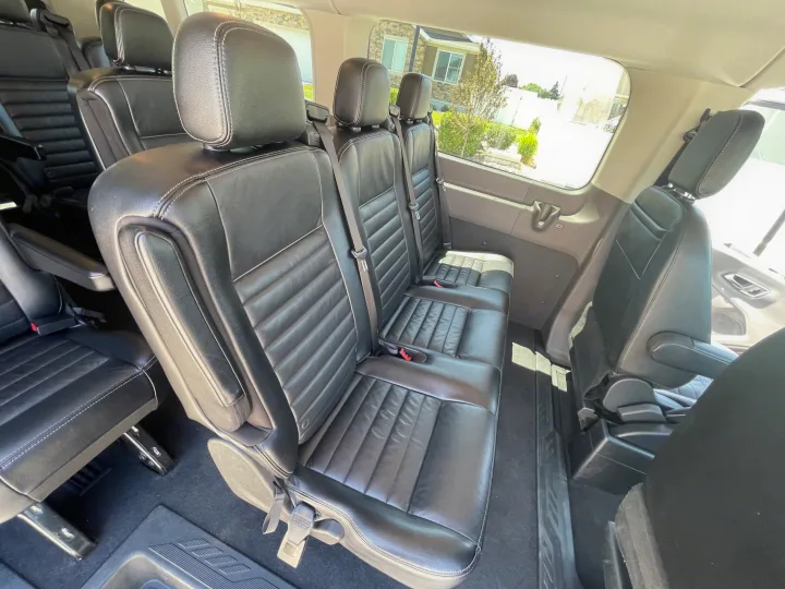 Spacious black leather seats inside a comfortable passenger van, ideal for your next rv rental adventure or group travel.. Ford Transit 350 XLT 2020