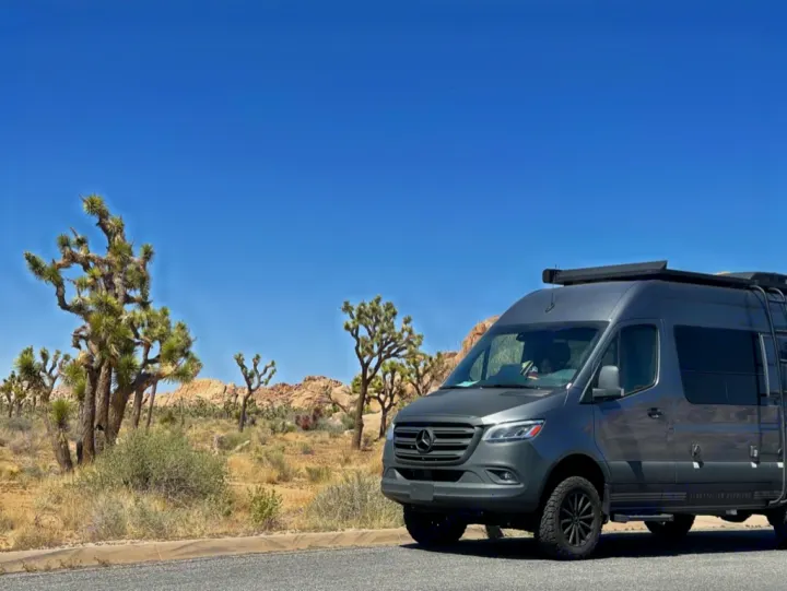 A grey Mercedes Sprinter RV rental van is parked amidst Joshua Trees in a sunny desert landscape.. Storyteller Overland Storyteller Overland Class B 2022