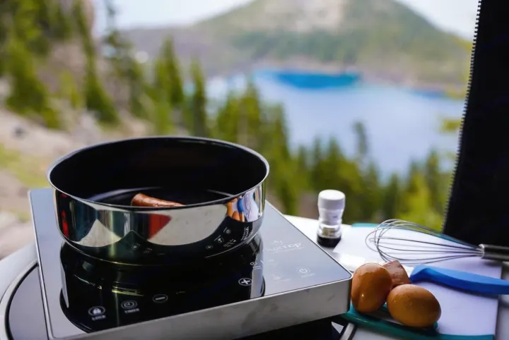 Cooking breakfast with a view from an RV rental: sausage, eggs, and whisk on an induction cooktop.. Storyteller Overland Storyteller Overland Class B 2022