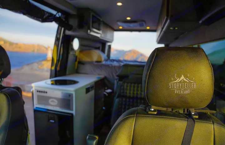 Inside a Storyteller Overland RV rental: equipped kitchen, cozy bed, and panoramic views of ocean and mountains.. Storyteller Overland Storyteller Overland Class B 2022