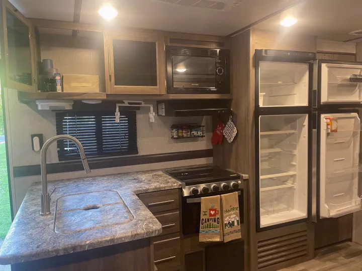 This RV rental features a full kitchen with a sink, stove, microwave, and refrigerator, ready for your next adventure.. Crossroads RV Zinger Lite 2021