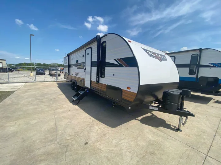 White & brown X-Lite travel trailer on a sunny lot. Ideal for your next RV rental adventure!. Forest River Wildwood X-Lite 2024