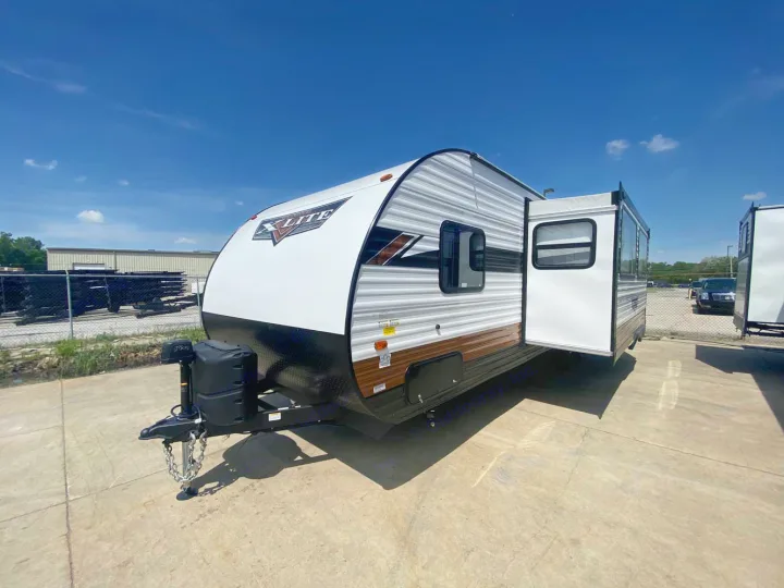 White & gray X-LITE travel trailer with extended slide-out, parked on concrete. Consider this RV rental for your adventures!. Forest River Wildwood X-Lite 2024