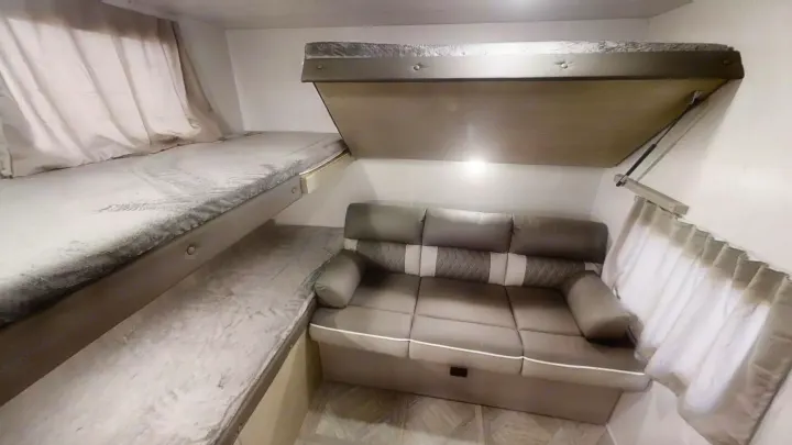 Inside an RV rental: upper and lower bunk beds, a comfortable sofa, and a cleverly designed drop-down bed maximize space.. Forest River Wildwood X-Lite 2024