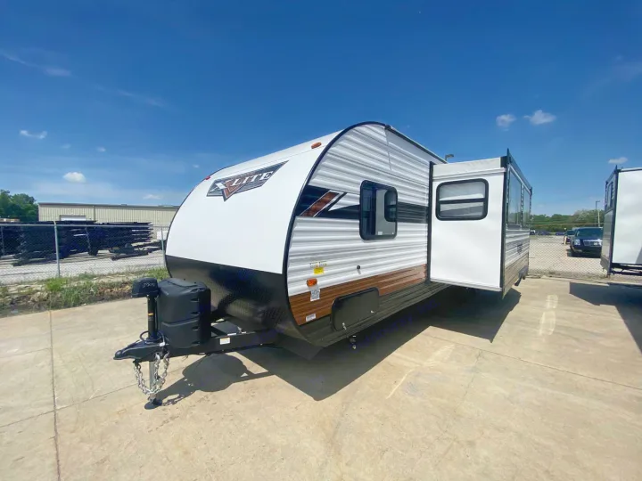 Spacious X-Lite travel trailer for RV rental. This white and gray RV features an extended pop-out, parked outdoors on concrete.. Forest River Wildwood X-Lite 2024