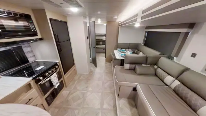 RV rental: Modern interior with kitchen, dining U-dinette, and large sofa. Hallway leads to bunk area for spacious travel.. Forest River Wildwood X-Lite 2024