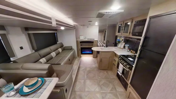 Spacious RV rental interior featuring a large sofa, full kitchen, and electric fireplace. Comfort and convenience on the go.. Forest River Wildwood X-Lite 2024
