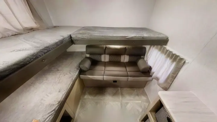 RV rental's compact interior: comfortable bunk beds and sofa seating provide versatile rest and lounge space for travelers.. Forest River Wildwood X-Lite 2024