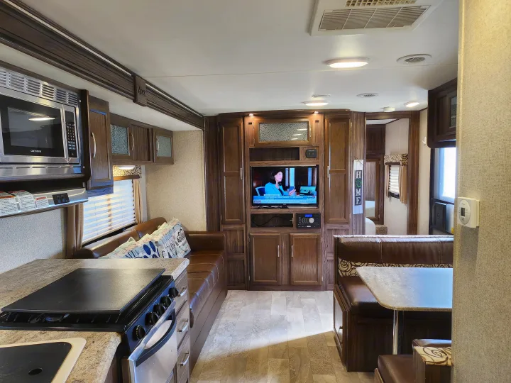 Spacious, modern RV rental interior featuring a full kitchen, living area with TV, and cozy dinette space.. Coachmen Apex 2017