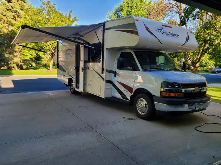 White Coachmen Freelander RV rental with extended awning on a sunny driveway.. Coachman Freelander 2019