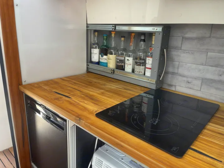 RV rental galley: Teak counter, induction cooktop, fridge, and a slide-out whisky bar with Macallan, Singleton, and more.. Other Transit 2022