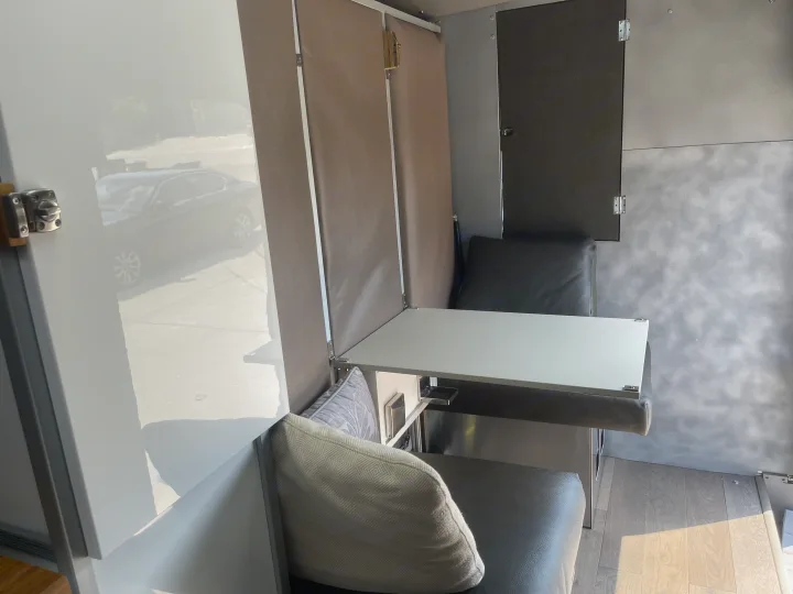 Sleek RV rental van interior featuring a practical dinette with two seats & a fold-down table. Ideal for remote work.. Other Transit 2022