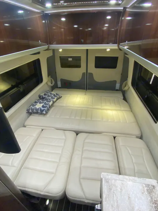 Inside a premium rv rental: a plush, white modular bed/lounge area with dark wood cabinets.. Airstream Interstate 2016