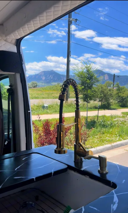Stunning mountain views from an RV rental's modern kitchen setup. Enjoy van life with this sleek sink & faucet!. Dodge Ram 1500 2019