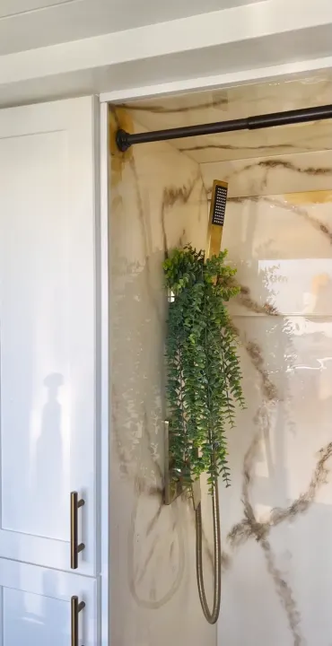 Modern RV rental shower featuring elegant marble walls, gold fixtures, and a decorative hanging plant next to white cabinets.. Dodge Ram 1500 2019