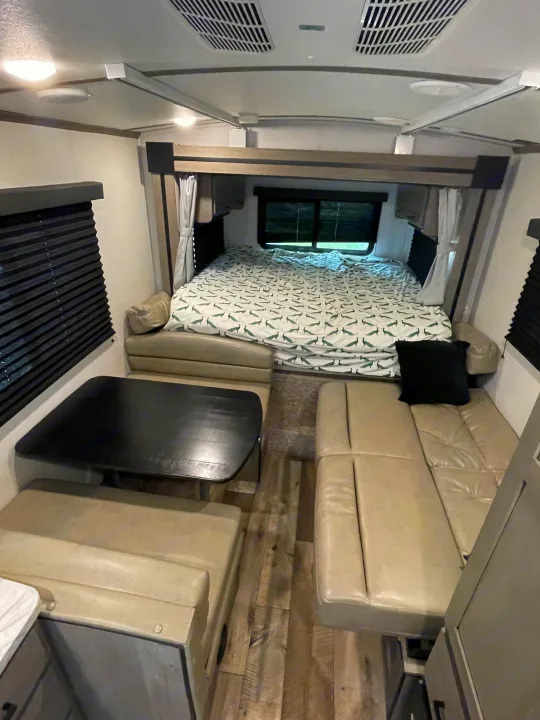 Cozy rv rental interior featuring a practical dinette, a bedroom with a unique peacock-patterned bed, and comfortable lounge seating.. Keystone RV Outback Ultra-Lite 2021