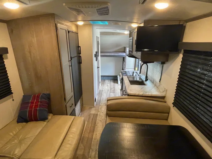 Spacious RV rental interior featuring a modern kitchen, cozy dinette, and rear bunk beds, ideal for travel.. Keystone RV Outback Ultra-Lite 2021