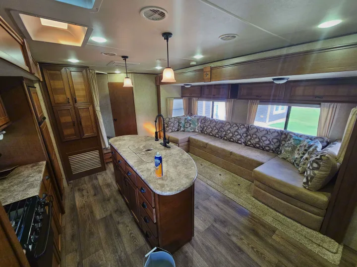 Spacious RV rental interior: comfortable living space with L-shaped couch, kitchen island, and wood floors.. Open Range RV Light 2014