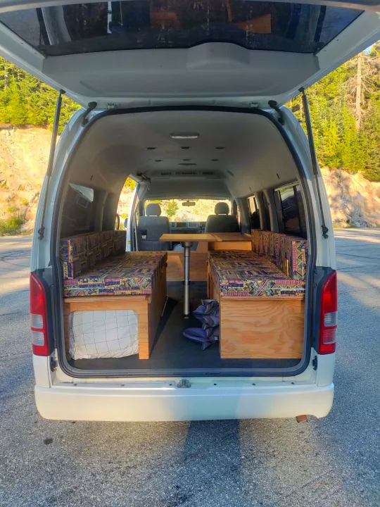 Camper van interior with colorful cushions & table, perfect for an RV rental adventure.. Toyota Hiace 2005