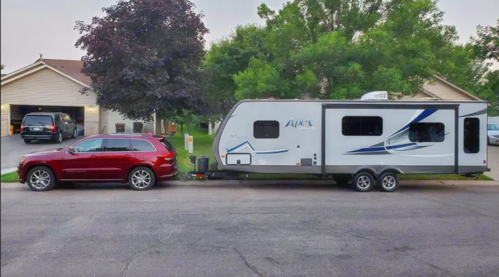 Red SUV towing a light grey travel trailer (Apex Ultra Lite), ready for an RV rental adventure.. Coachmen Apex 2017