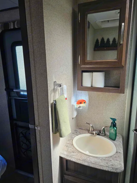 Inside an RV rental: compact bathroom vanity with sink, mirror, towel, and a fun camper nightlight.. Coachmen Apex 2017