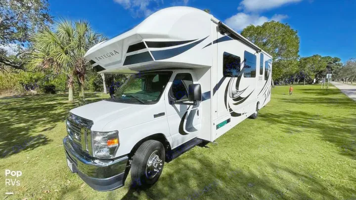 Entegra Class C RV rental: White motorhome with black/grey graphics, parked on sunny green grass.. Entegra Coach Odyssey 2021